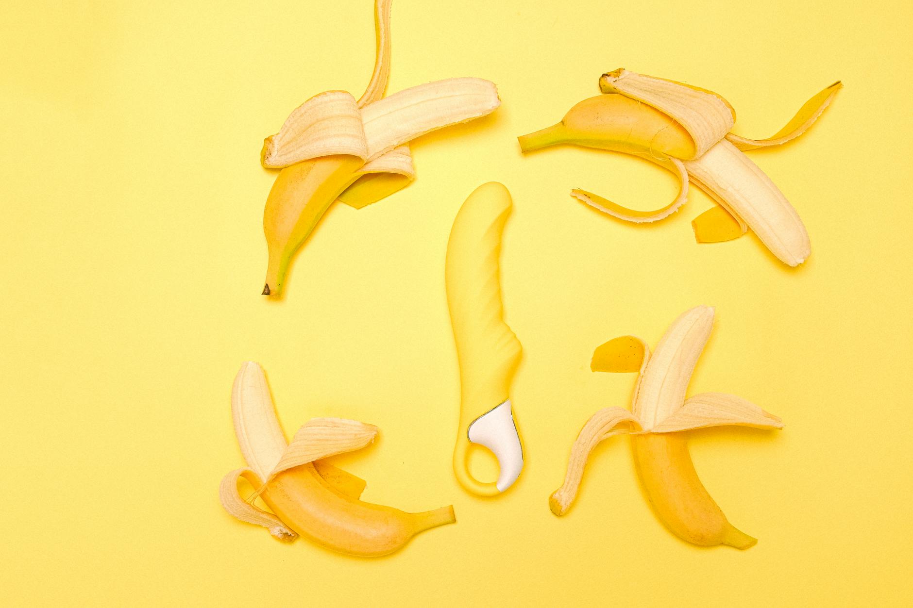 A yellow lemon vibrator surrounded by peeled lemons on a bright yellow background