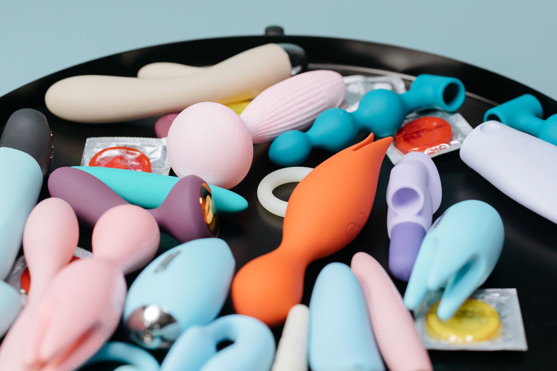 A collection of colorful vibrators on a black surface, including various stimulation styles