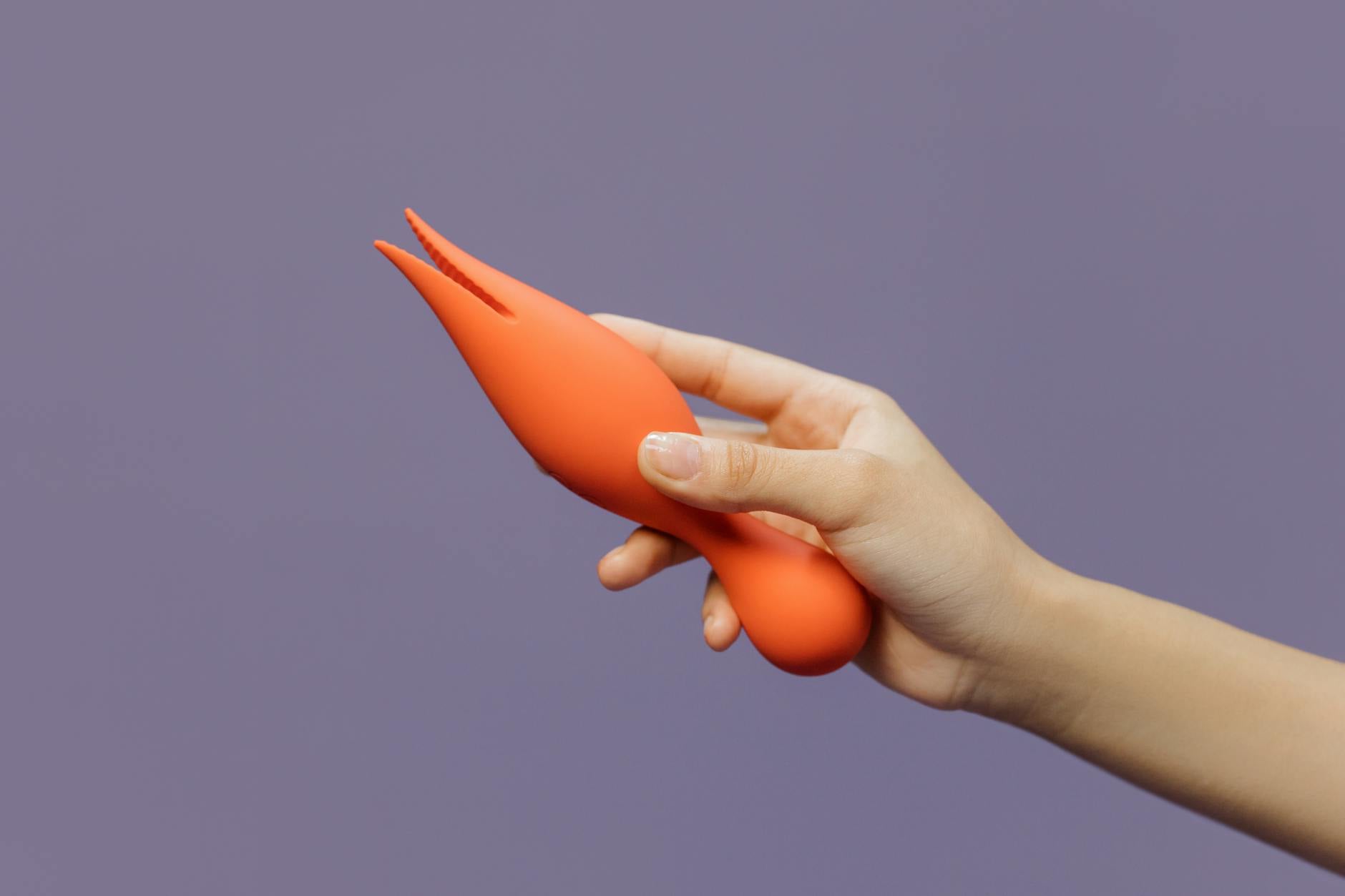 A hand holding a lemon vibrator against a minimalistic purple backdrop, showcasing modern sensuality and pleasure technology.