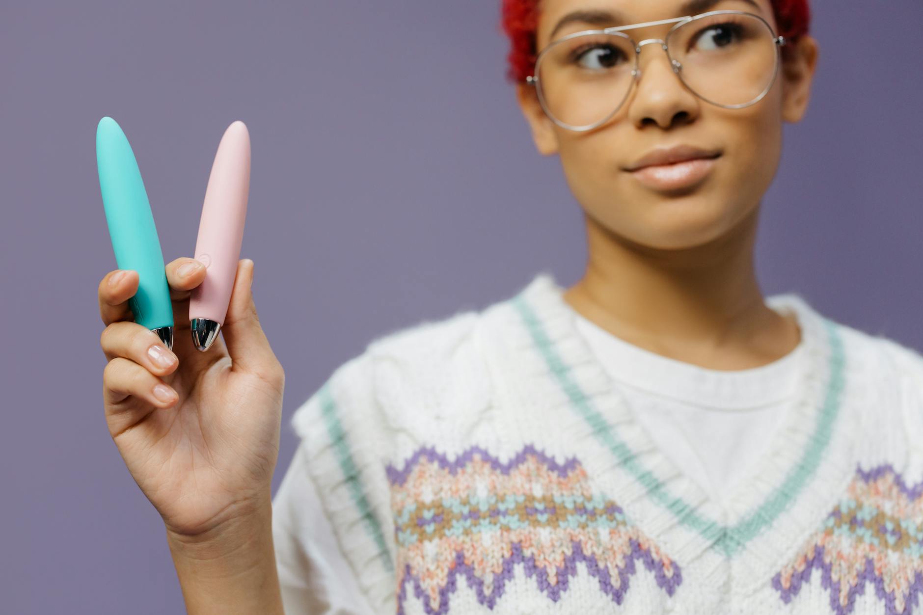 Woman holding colorful lemon vibrators against a purple background