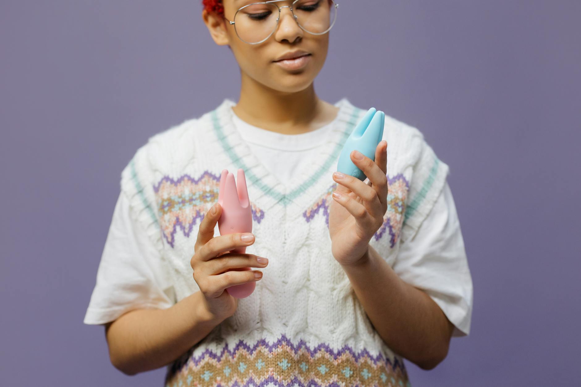 Woman holding blue and pink silicone vibrators thoughtfully, symbolizing intentional choice and body autonomy
