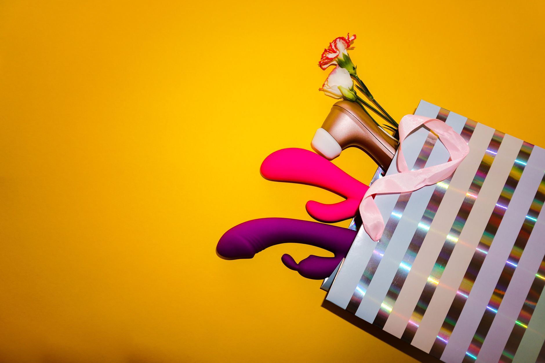 A hand holding an orange vibrator against a minimalistic purple backdrop, showcasing modern sensuality and authentic pleasure reclamation.
