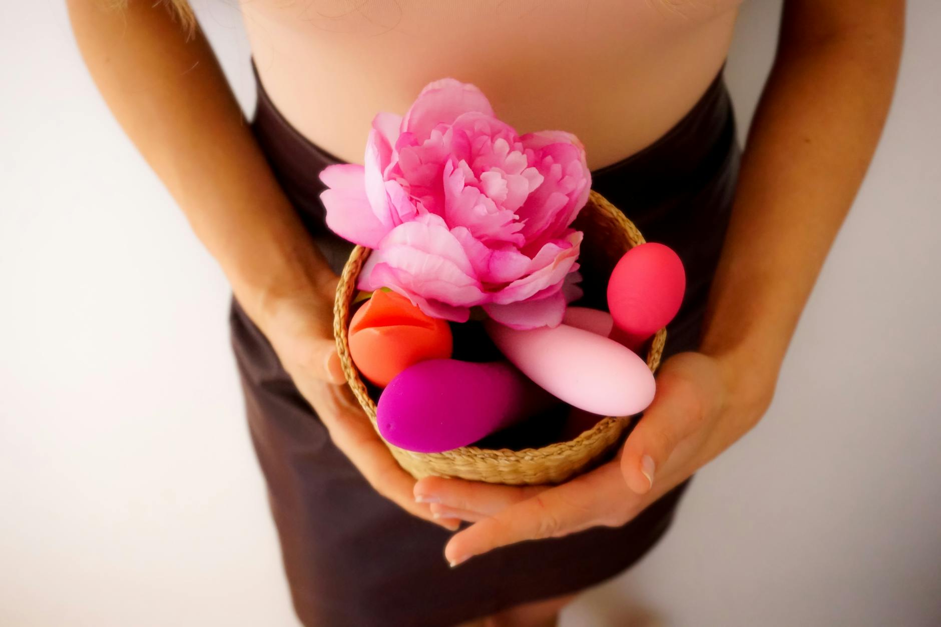 Hand holding a lemon on pink background, representing lemon vibrators and suction stimulation